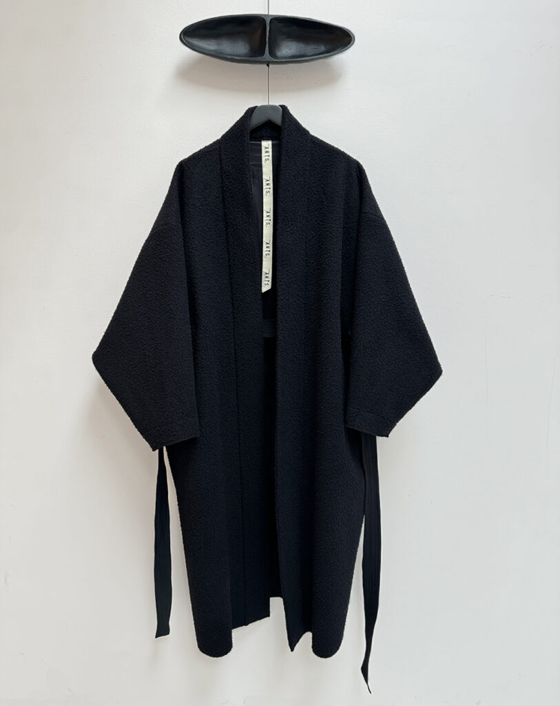 Frontside oversized pilled black wool coat in kimono style with padded and topstitched long belt