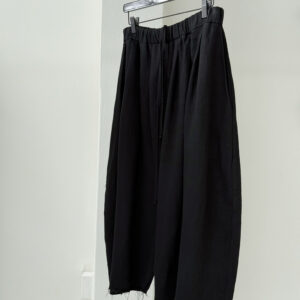 Sideview of round shaped culottes with multiple waistband pleats made in black Japanese linen corduroy fabric