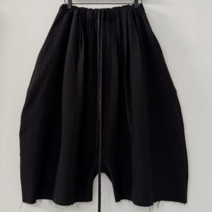 Frontside of round shaped unisex culottes with multiple waistband pleats made in black Japanese wool/linen fabric