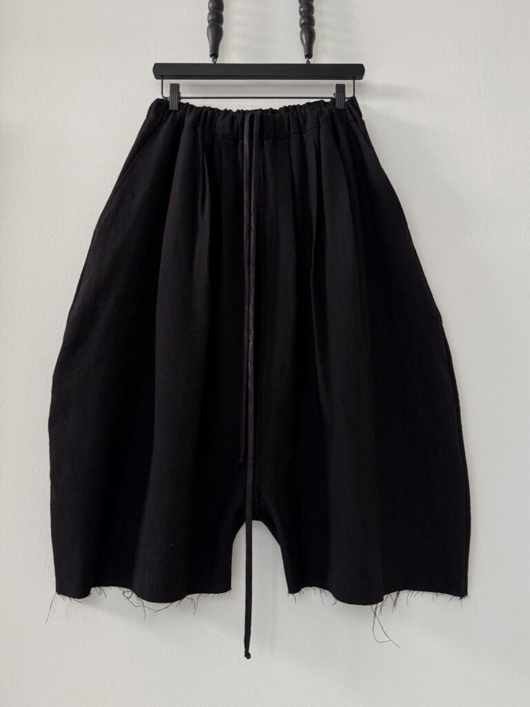 Frontside of round shaped unisex culottes with multiple waistband pleats made in black Japanese wool/linen fabric